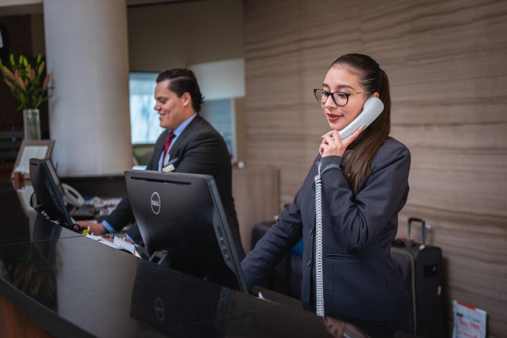 Cheerful receptionists checking in at a hotel front desk, symbolizing an easy and smooth check-in experience.