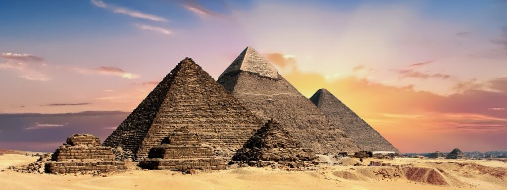 The Pyramids of Giza standing majestically under a golden sky, a must-see landmark featured in this Egypt travel guide.