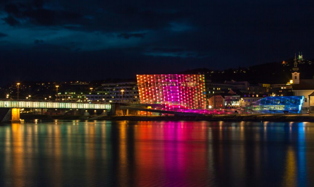 Ars Electronica Center in Linz, Austria, a futuristic museum and one of the best things to do in Linz, featuring modern glass architecture with lights reflecting on the Danube River.