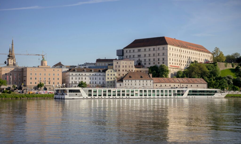 Danube River in Linz, Austria with a sightseeing cruise boat sailing on the water, one of the best things to do in Linz, and city scenery along the riverbanks.