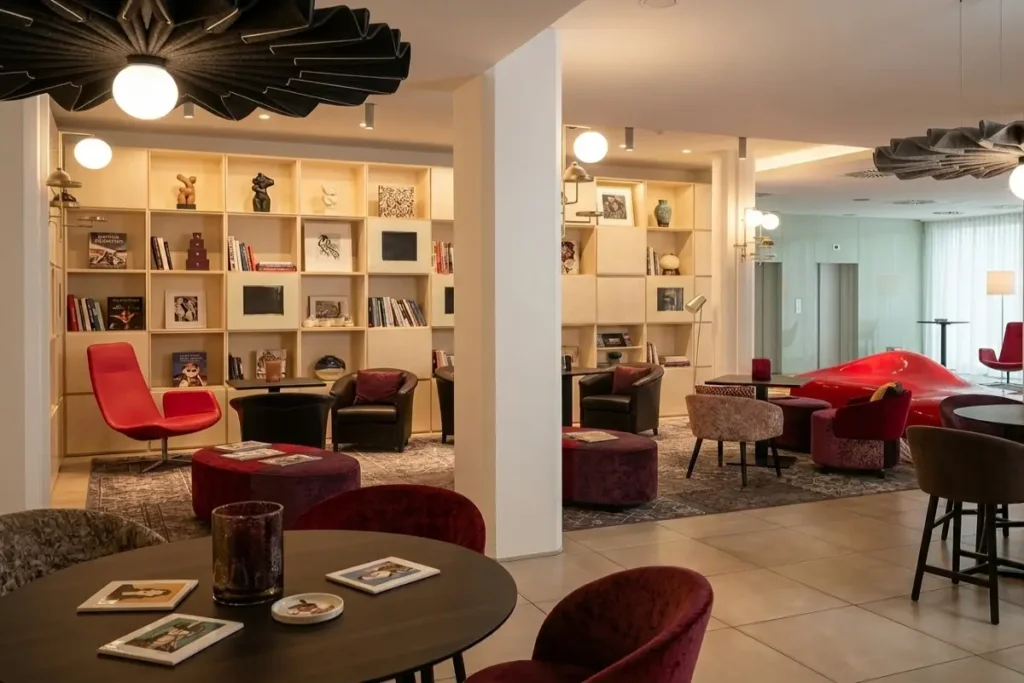 he artistic and modern lobby lounge at Arte Hotel Linz featuring contemporary chairs, unique lighting, and bookshelves.