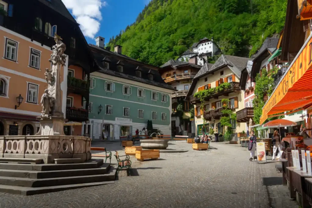 Hallstatt Market Square surrounded by colorful traditional houses, balconies, cafés, and the Holy Trinity statue.