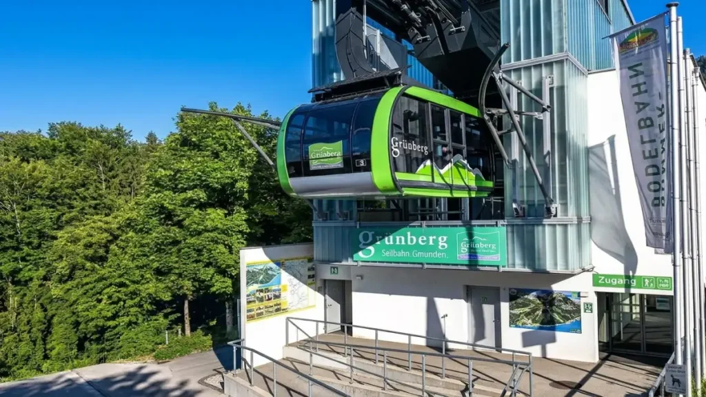 Grünberg cable car station in Gmunden, Austria with a green gondola beside the forest