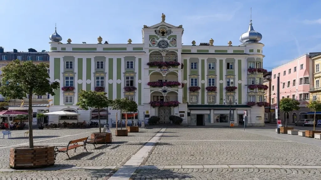 Rathausplatz in Gmunden, Austria with the historic town hall, cobblestone square, benches, trees, and colorful old town buildings