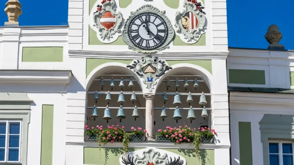 Ceramic bells on the Gmunden Town Hall facade with a historic clock, flower boxes, and decorative details
